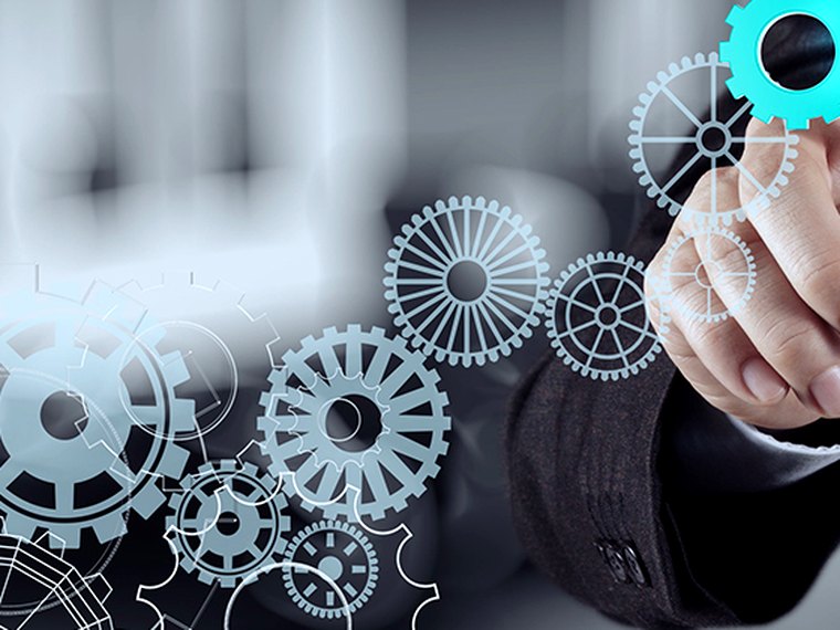 A hand engaging one gear in a connected system, representing Enerov Industry's mission
